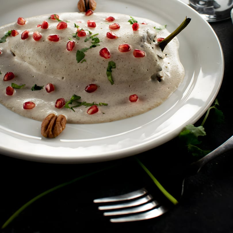 Chiles en nogada, a Mexican dish, topped with creamy sauce, pomegranate seeds, and pecans.