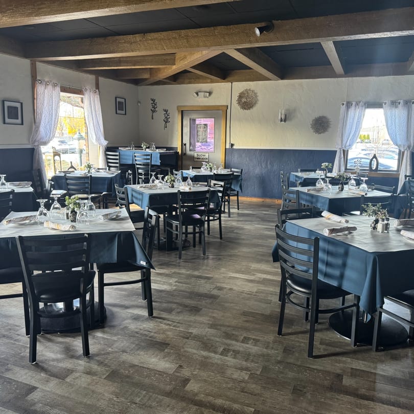 Interior of Tavos at the Grove, a Mexican restaurant, with set tables, blue tablecloths, and wooden beams.